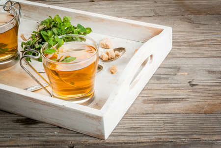 Homemade tea from mint leaves in tray on a rustic wooden table, copy spaceの写真素材