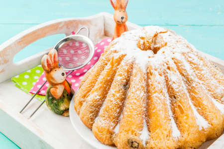 Beautiful Easter ring cake and small Easter cupcakes decorated with icing sugar, on a decorated...