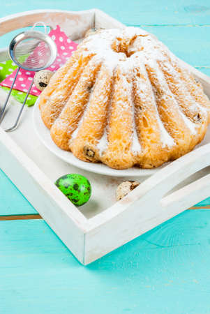 Beautiful Easter ring cake and small Easter cupcakes decorated with icing sugar, on a decorated...