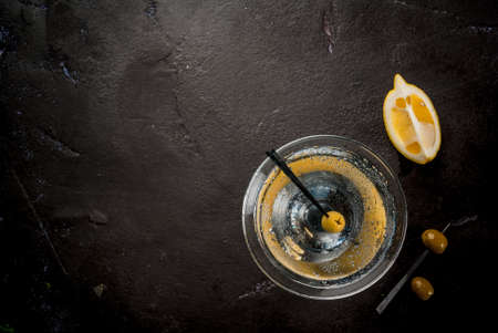 Cocktail martini with olives and a lemon on a black concrete stone table, copy space top viewの写真素材