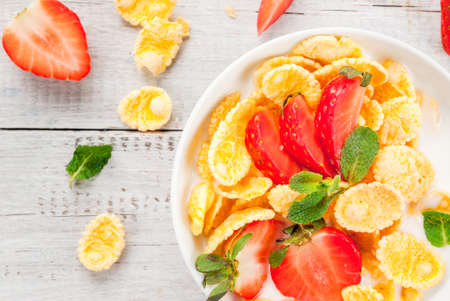 Summer light breakfast: homemade organic yogurt with cornflakes and fresh strawberries. On a white...