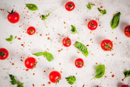 Preparation of food background: fresh tomatoes, basil leaves, parsley and seasoning, on a white...