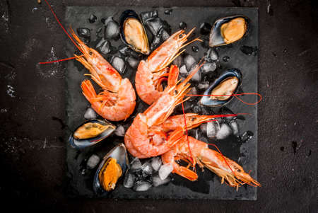 Prepared for cooking dinner seafood - shrimp and mussels on ice, on a cutting slate board, with lemon and seasonings. Top view, copy spaceの写真素材