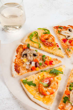 Slices of two kinds of dietary vegetarian pizza on a white stone table: with mushrooms and shrimps.With white wine in glass, copy spaceの写真素材