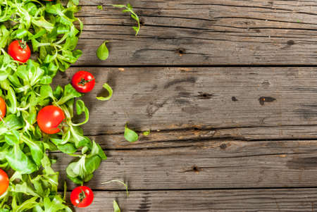 Salad leaves and tomatoes on an old rustic wooden table. View from above, copy spaceの写真素材