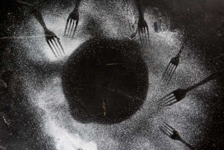 Black stone table sprinkled with powdered sugar. With traces of forks. Concept (idea) - guests,...