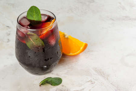 Traditional Spanish summer refreshing drink, cocktail, Tinto de verano. With wine, ice and pieces of fresh orange. On white stone  table, copy spaceの写真素材