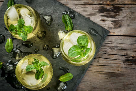 Traditional Spanish alcoholic drink, Rebujito cocktail - white wine, carbonated water (soda), mint, lemon juice. On a rustic wooden table, three glasses. Copy space top viewの写真素材