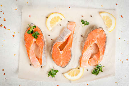 Raw  trout fish, salmon. On a white kitchen table, with herbs (parsley), lemon and spices for cooking. Top viewの写真素材