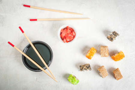 Concept of Japanese food: sticks and sushi, soy sauce and pickled ginger on a white stone table. Top...
