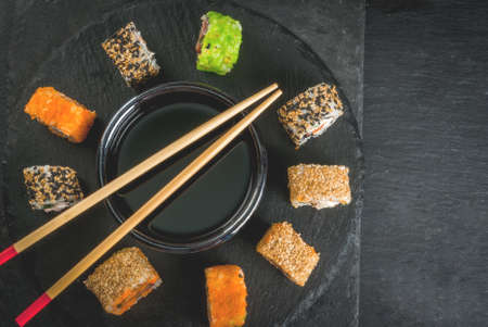 Concept of Japanese food: sticks and sushi, soy sauce and pickled ginger on a black slate stone table. Top view copy spaceの写真素材