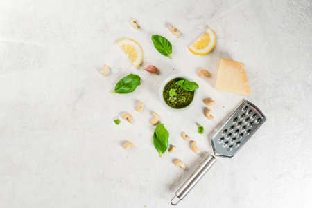 Italian and Mediterranean cuisine. Pesto sauce with ingredients on a white stone table: Parmesan cheese, cashew nuts, butter, lemon, basil. Top view copy spaceの写真素材