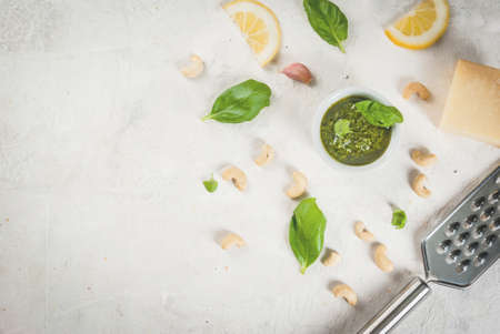 Italian and Mediterranean cuisine. Pesto sauce with ingredients on a white stone table: Parmesan cheese, cashew nuts, butter, lemon, basil. Top view copy spaceの写真素材