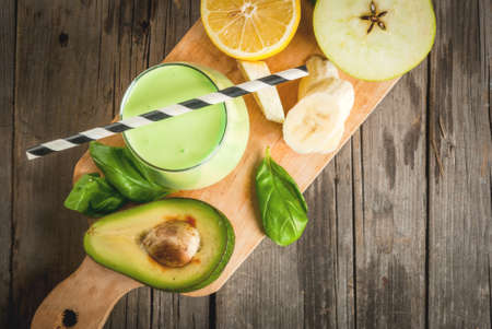 Healthy food. Dietary breakfast or snack. Green smoothies from yoghurt, avocado, banana, apple, spinach and lemon. On a rustic wooden table, with ingredients. Copy space top viewの写真素材