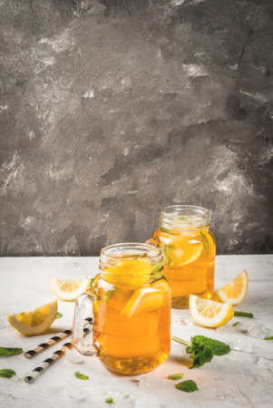 Chilled summer tea with ice, mint and lemon. Two portions in Mason Jars on a white stone table. Copy spaceの写真素材