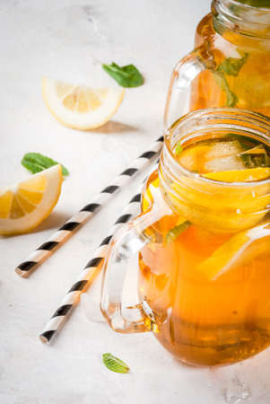 Chilled summer tea with ice, mint and lemon. Two portions in Mason Jars on a white stone table. Copy spaceの写真素材