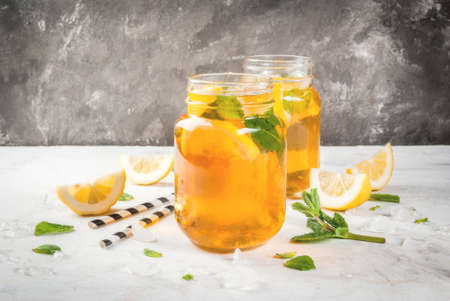 Chilled summer tea with ice, mint and lemon. Two portions in Mason Jars on a white stone table. Copy spaceの写真素材