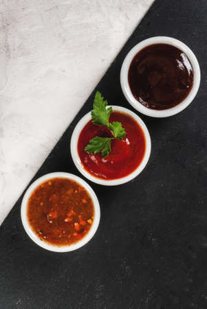 Three kinds of red tomato sauce on a white stone table: traditional classic ketchup, barbecue sauce, sweet and sour Chinese sauce. Top view copy spaceの写真素材
