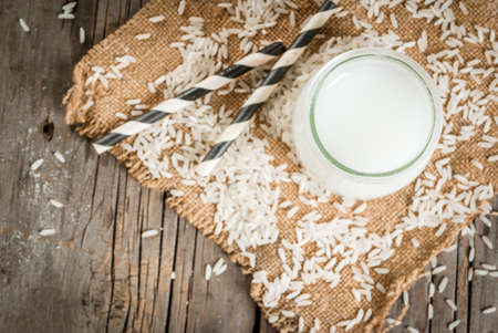 Rice milk, with rice grains. On a rustic wooden table. With a striped tube for drinking. Copy space top viewの写真素材