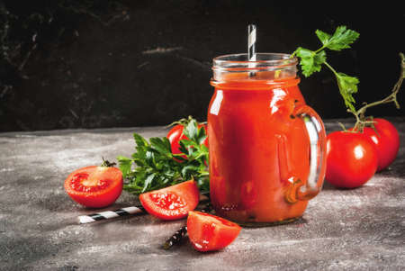 Tomato juice in mason jar, with tomatoes and greens On a gray concrete table. Copy spaceの写真素材