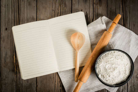 Baking background. Tools and ingredients for baking on the old rustic wooden table. Book notepad for recipes. Top view copy spaceの写真素材