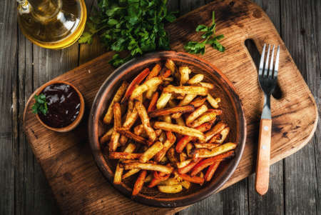 Homemade food. Fried French potatoes and carrots, on a serving board, with barbecue sauce on a rustic wooden table. Top viewの写真素材