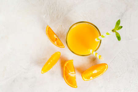 Drink. Orange juice in a glass, with orange slices on the table. With a mint leaf and two striped straws. Top view, selection focus, copy spaceの写真素材