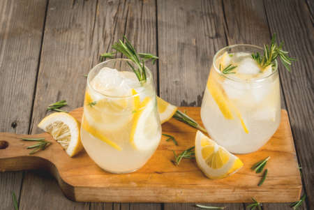 Summer refreshments. Detox water. Lemonade. Tonic with ice, lemon and rosemary, on an old wooden rustic table. Copy spaceの写真素材