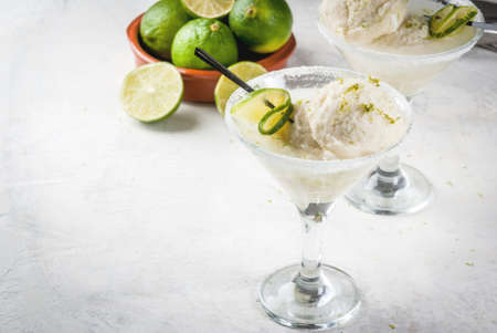 Refreshing summer alcoholic cocktail floating margarita. With tonic and salted lime ice cream with zest. With a lime garnish. On a white concrete table. Copy spaceの写真素材