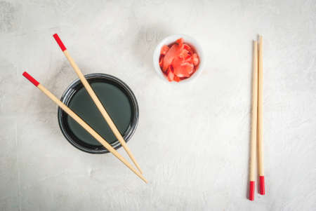 Concept of Japanese food: sticks for sushi, soy sauce and pickled ginger on a white stone table. Top view copy spaceの写真素材