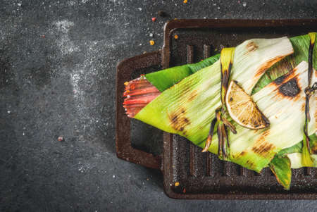 Gish. seafood. Asian and Eastern cuisine. Red tilapia roasted on a grill in leaves of leeks with slices of lime, herbs and spices. In the frying pan, grill. Top view copy spaceの写真素材