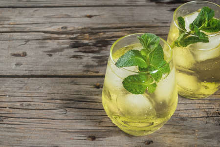 Traditional Spanish alcoholic drink, Rebujito cocktail - white wine, carbonated water (soda), mint, lemon juice. On a rustic wooden table, two glasses. Copy spaceの写真素材