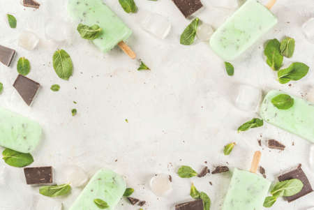 Homemade ice cream. Summer desserts. Refreshing ice cream with mint and chocolate. All the ice cream in the molds, one without it in the foreground. On a white stone table.の写真素材