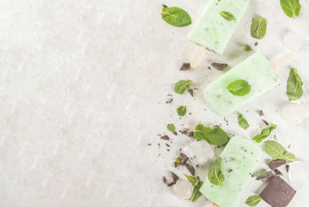 Homemade ice cream. Summer desserts. Refreshing ice cream with mint and chocolate. All the ice cream in the molds, one without it in the foreground. On a white stone table.の写真素材