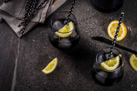 Trendy food. Summer refreshment drinks. Detox and diet concept. Black lemonade with charcoal, ice, lemon juice and lemon. On a home stone table, with black straws for drinking. Copy spaceの写真素材