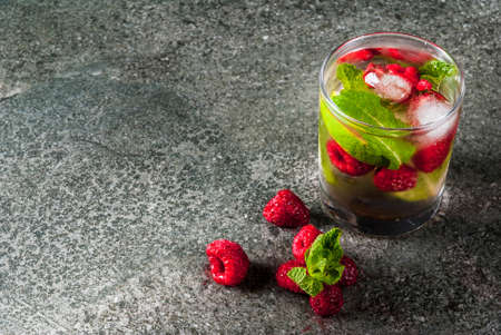 Set of traditional summer refreshing drinks berry mojito. With lime, mint leaves, raspberries. With the ingredients on a dark stone table. Copy spaceの写真素材