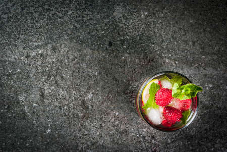 Set of traditional summer refreshing drinks berry mojito. With lime, mint leaves, raspberries. With the ingredients on a dark stone table. Copy space top viewの写真素材