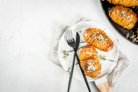 American traditional home cooking. The vegan diet. Homemade Hasselback Potato with Fresh Herbs and cheese. On white table, copy space top viewの写真素材