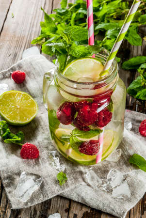 Summer drinks, cocktails. Vegan food. Infused detox water with lime, mint and fresh organic raspberries. On an old rustic wooden table with ingredients. Copy spaceの写真素材