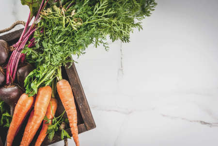Summer, autumn harvest. Fresh organic farm vegetables in a wooden box on a white marble table -...