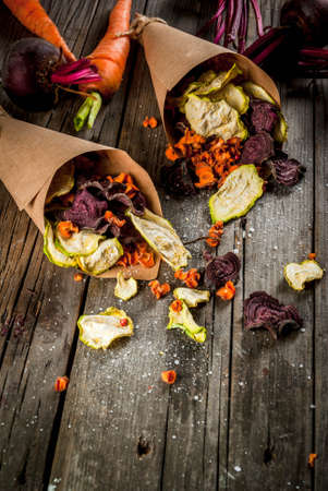 Organic diet food. The vegan diet. Dried vegetables. Homemade chips from beets, carrots and zucchini. On old wooden rustic table, with fresh vegetables. Copy spaceの写真素材