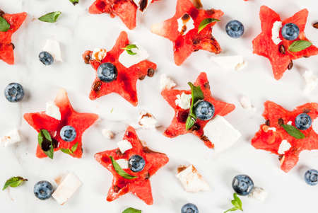 Summer fruit berry salad: watermelon sliced in the form of stars, blueberries, feta cheese and balsamic sauce. On white marble table. Top view, pattern, food backgroundの写真素材