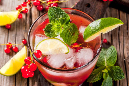Ideas of summer drinks, dietary healthy cocktails. Mojito from lime, mint and red currant. On the old rustic wooden table, with the ingredients. Copy spaceの写真素材