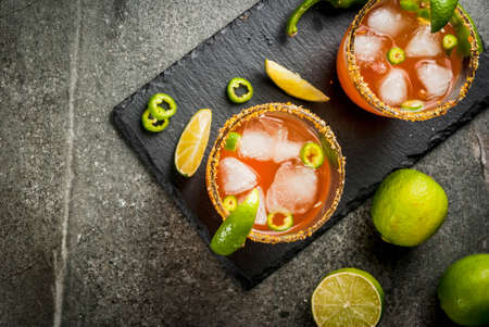 Alcohol. Traditional Mexican South American cocktail. Spicy michelada with hot jalapeno peppers and lime. On a dark stone table. Copy space top viewの写真素材