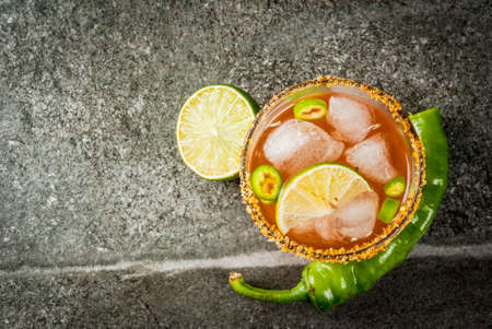 Alcohol. Traditional Mexican South American cocktail. Spicy michelada with hot jalapeno peppers and lime. On a dark stone table. Copy space top viewの写真素材