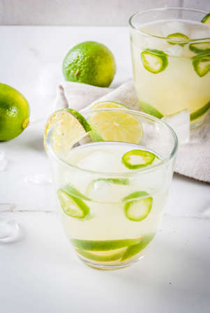 Mexican traditional refreshing drink Fresh Lime and Jalapeno Margarita with tequila, hot pepper and lime (lemon). On a white marble kitchen table. Copy spaceの写真素材