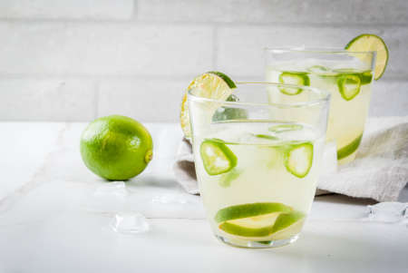 Mexican traditional refreshing drink Fresh Lime and Jalapeno Margarita with tequila, hot pepper and lime (lemon). On a white marble kitchen table. Copy spaceの写真素材