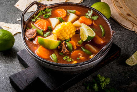 Autumnal vegetable stew. Mexican traditional vegetable soup Mole de olla with meat, potatoes, carrots, beans, corn and lime. Copy spaceの写真素材
