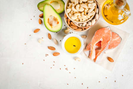 Healthy food. Products with healthy fats. Omega 3, omega 6. Ingredients and products: trout (salmon), flaxseed oil, avocado, almonds, cashews, pistachios. On a white stone table. Copy space top viewの写真素材