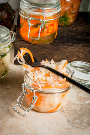Concept of a fermented meal. Home canned food and billets. Vegan food. Vegetables. Cans of canned salsa, sauerkraut, marinated carrots, kimchi and cauliflower broccoli. Home kitchen table. copy spaceの写真素材
